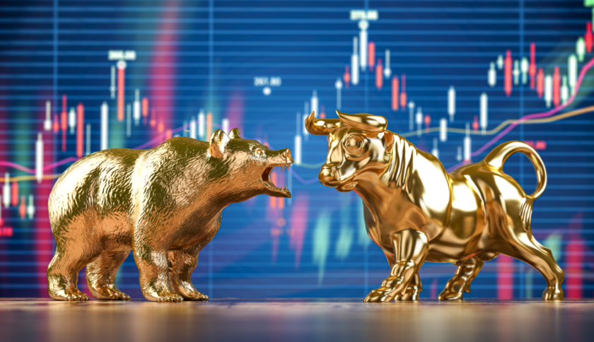 Due statuette dorate, rappresentanti un orso e un toro, si fronteggiano davanti a uno schermo che riporta il grafico a candele di un asset class
