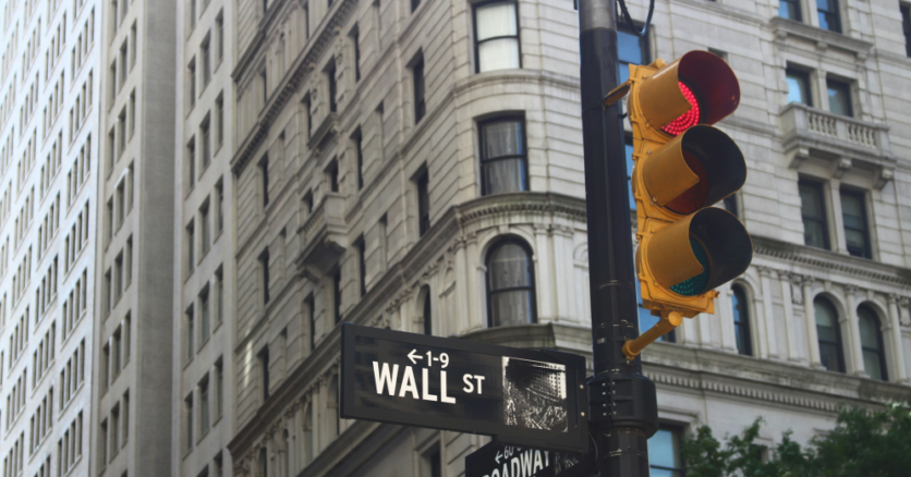 Un semaforo rosso sovrasta la segnaletica che indica Wall Street, la strada dove ha sede il Nyse