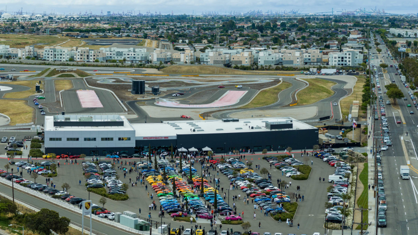 Il centro tecnico di Porsche durante una celebrazione. Attorno al centro, visto da lontano e dall'alto, sono parcheggiate centinaia di auto Porsche