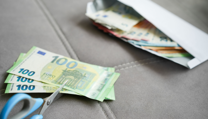 Un paio di forbici tagliano una mazzetta fatta da banconote del valore di 100 euro, a rappresentare l'effetto dell'inflazione