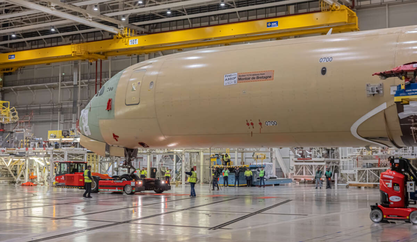 Officina hangar Airbus: un A250 senza insegne trainato da un carrello viene sottoposto a operazioni di modifica