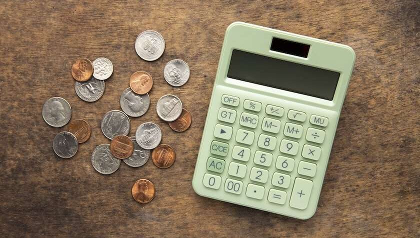 Calcolatrice e monete su tavolo in legno, simbolo del calcolo dell’Irap 2026 per imprese e professionisti e delle imposte da pagare