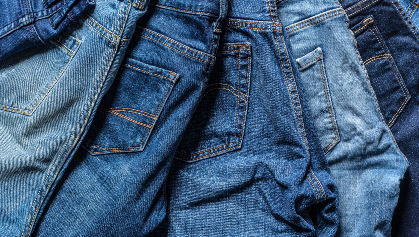 Cinque paia di jeans di differenti tonalità di blu allineati