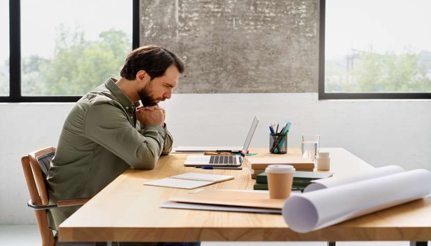 Uomo preoccupato al computer mentre controlla documenti – pensione anticipata lavori usuranti 2026