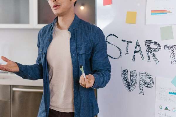 Immagine di un giovane che spiega il modello di business di una startup in una lavagna