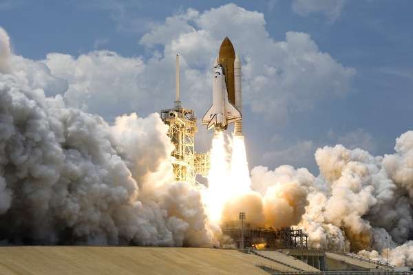 Lancio dello Space Shuttle dalla rampa di Cape Canaveral tra nuvole di fumo e fiamme
