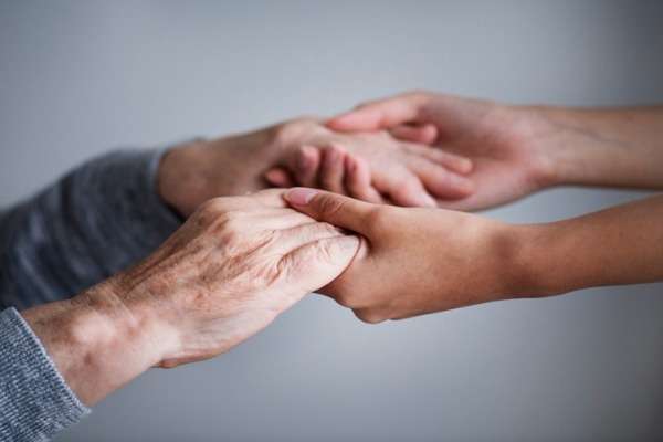 Mani giovani che sostengono mani anziane, simbolo di assistenza e tutela, usate per illustrare le novità su Invalidità civile e legge 104 per gli over 70.