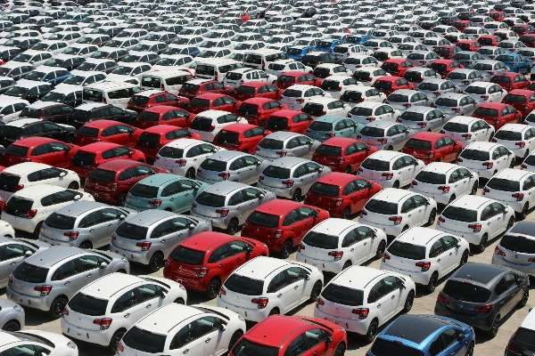 uto nuove parcheggiate in file su un piazzale industriale viste dall'alto