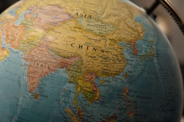 Mappamondo realistico con focus sull’Asia, in evidenza Cina, India e Sud-Est asiatico, illuminazione calda e profondità di campo ridotta.