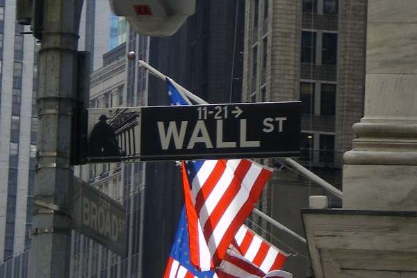 Cartello stradale di Wall Street con bandiere americane sullo sfondo, nel cuore del distretto finanziario di New York