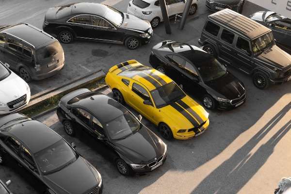 Parcheggio con auto di diversi segmenti e alimentazioni visto dall'alto, con una Ford Mustang gialla al centro circondata da berline e SUV scuri.