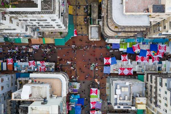 Strade di Hong Kong si incrociano viste in verticale dall'alto. Sono presenti numerose tende colorate che indicano la presenza di locali o mercati.