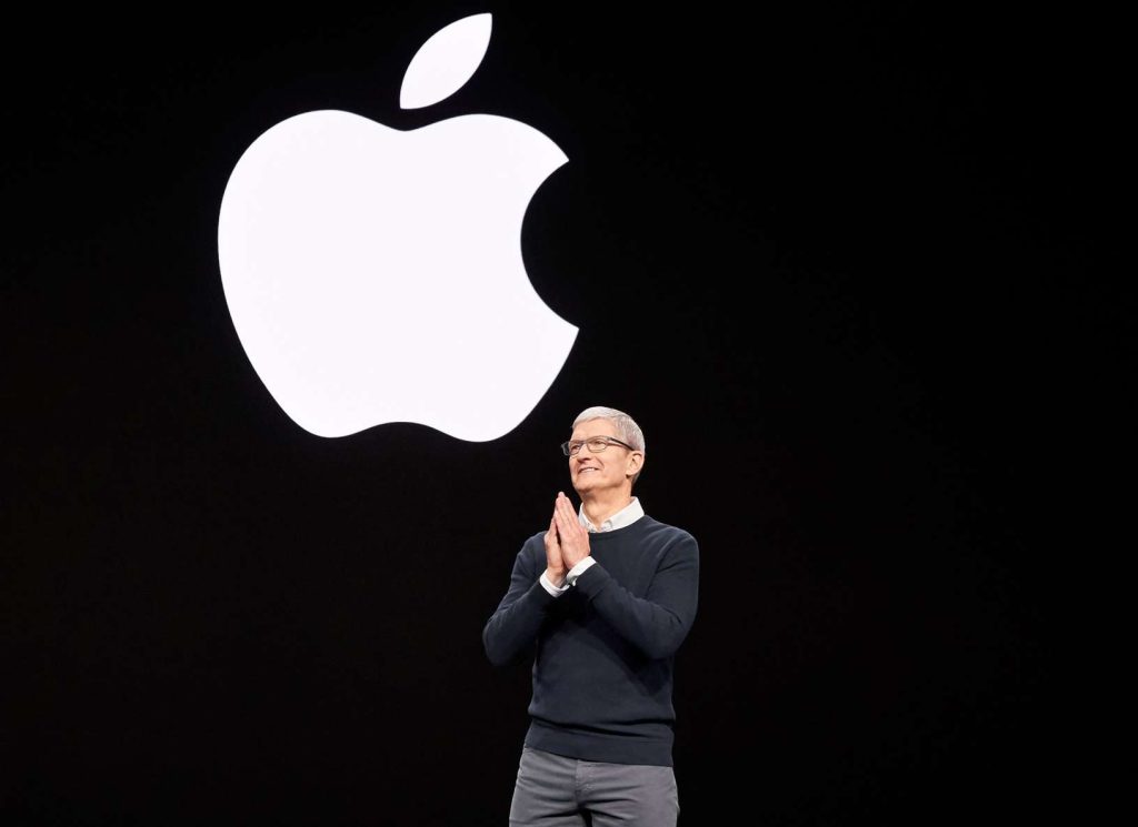 Tim Cook sul palco del keynote Apple davanti al logo illuminato