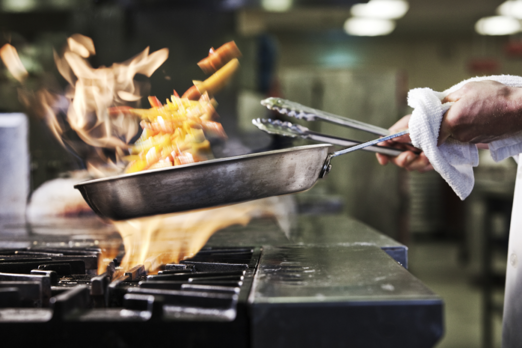 La preparazione di un piatto flambé nella cucina di un ristorante.