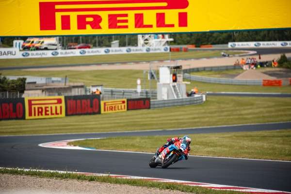 Il pilota di moto Valentin Dibiase sfreccia in pista con la sua moto davanti a cartellonistica Pirelli.