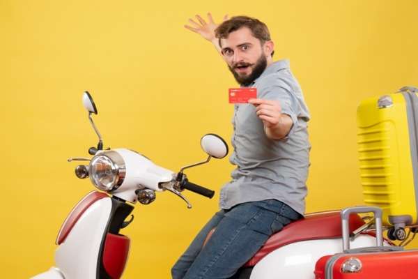 Ragazzo su scooter con valigia e carta di credito per incentivi Bonus Moto 2026