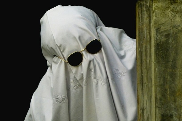 Una persona vestita da fantasma con gli occhiali da sole