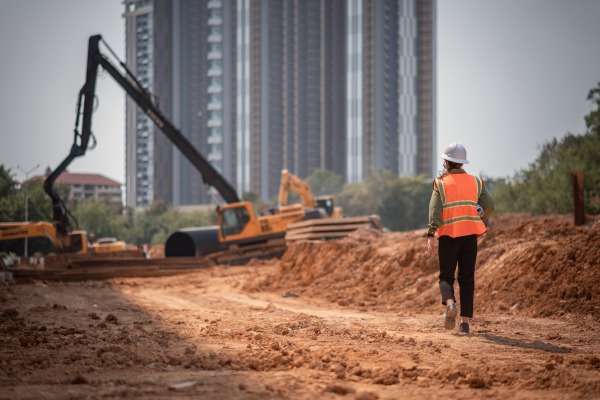 Un operaio cammina, di spalle, all'interno di un cantiere di costruzioni.
