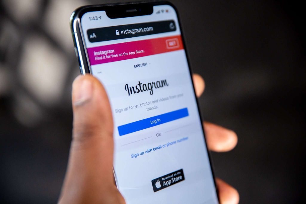Mano che regge uno smartphone con la schermata di login di Instagram, al centro dell'indagine UE su Meta per design che crea dipendenza