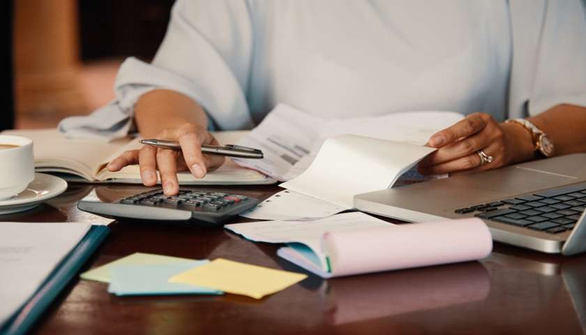Donna al computer mentre consulta documenti finanziari