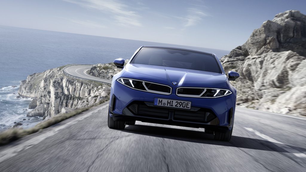 BMW i5 blu su strada panoramica costiera con scogliera e mare sullo sfondo