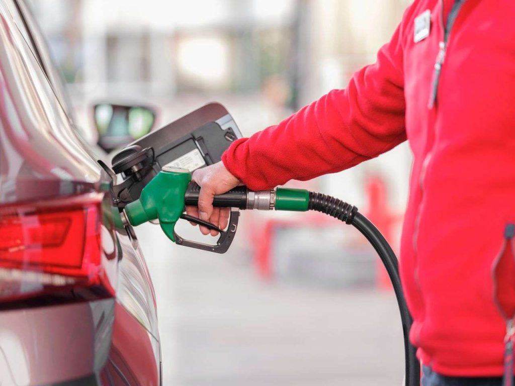 Addetto in giacca rossa rifornisce di benzina un'auto al distributore