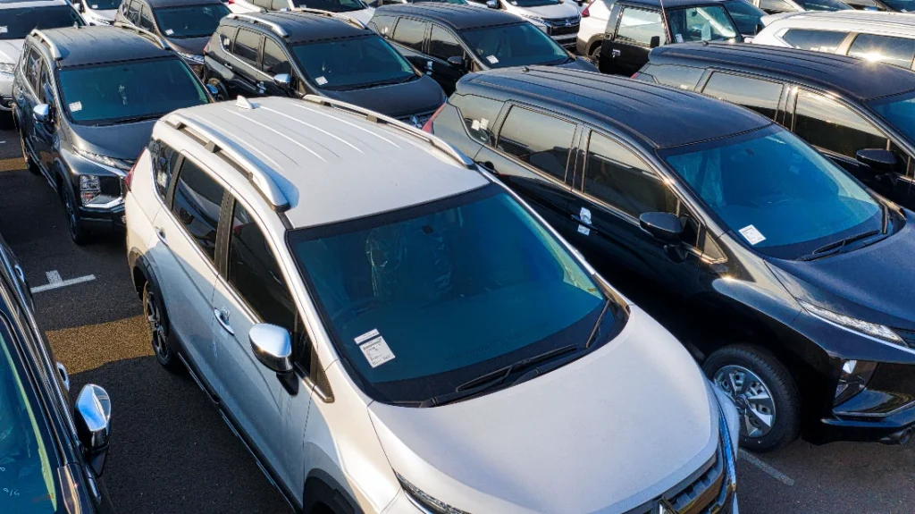 Ampio piazzale con centinaia di auto aziendali nuove parcheggiate in file ordinate, in attesa di consegna