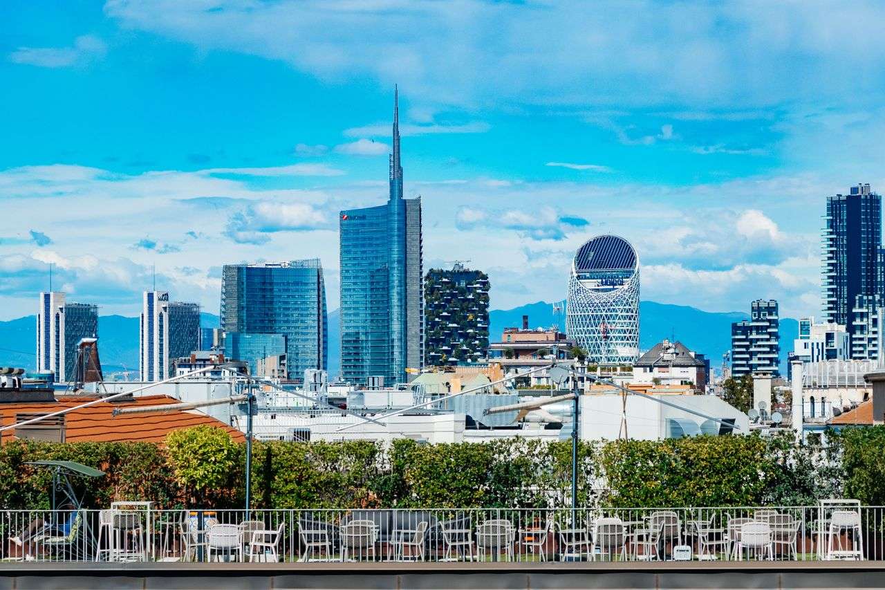 Vista dello skyline di Milano con la Torre UniCredit, il Bosco Verticale e i grattacieli del quartiere Porta Nuova sotto un cielo azzurro